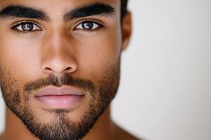 This handsome man presents a captivating expression with defined features and deep eyes, creating an engaging atmosphere in soft lighting photo