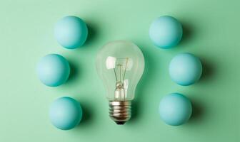 A bright bulb glows center-stage, flanked by four blue spheres on a pastel green background photo