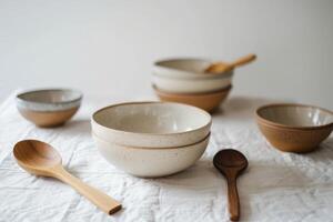 Beautifully crafted ceramic bowls of various sizes and colors displayed alongside wooden spoons photo