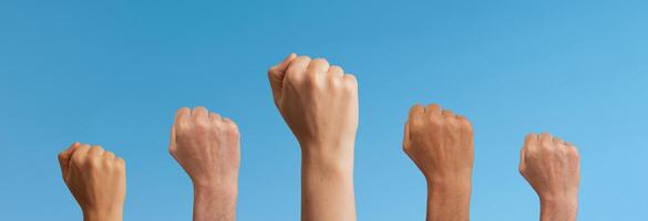Clenched fists raised in unity, symbolizing freedom and feminist power. Women and girls in a crowd, photo