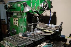Detailed view of an old milling machine in an industrial workshop with tools scattered around, representing skilled craftsmanship in metalworking photo