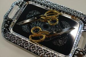 Golden scissors and ornate silver tray displayed elegantly on a surface in a bright room for a creative event photo