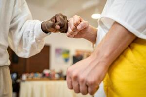 Two friends sharing a moment of connection through a friendly fist bump in a warmly lit indoor space photo