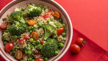 A bowl of quinoa salad with broccoli, tomatoes and peas photo