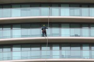 A man on a rope cleaning the windows of a tall building photo