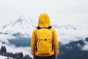A person with a yellow backpack standing on top of a mountain photo