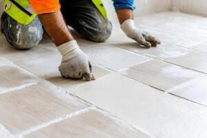 A man is laying tile on a floor photo