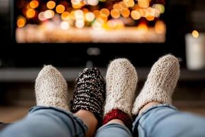 Two people wearing knitted socks and sitting on a couch with a television in the background photo