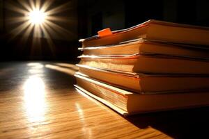 A stack of books on a wooden table with sunlight shining through the window photo