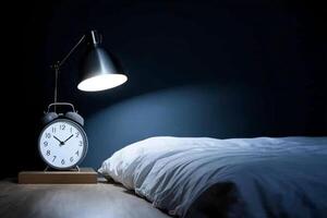 An alarm clock sits on a table next to a bed photo