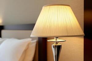 A lamp on a bed next to a white pillow photo