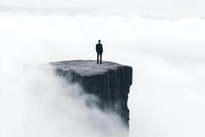 A man standing on top of a cliff in the middle of the clouds photo