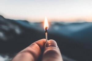 A person holding a lit match in front of a mountain photo