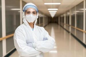 A woman in a white coat and mask standing in a hallway photo