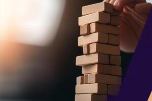 A person holding a wooden block tower with the words, how to build a business photo