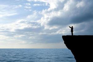 A man standing on the edge of a cliff looking out over the ocean photo
