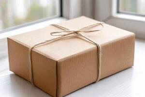 A brown cardboard box tied with a string on a window sill photo