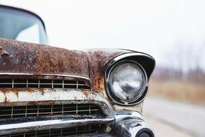 An old rusty car is parked on the side of the road photo