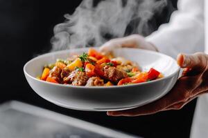 A chef holding a bowl of food with steam coming out of it photo
