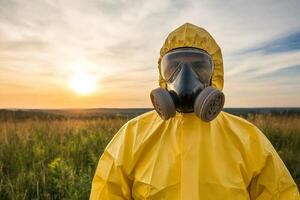 A man in a yellow rain suit and gas mask standing in a field photo