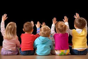 A group of children sitting on the floor with their hands up photo