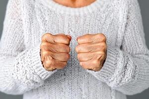 An older woman in a sweater is showing her fists photo