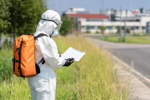 A person in a protective suit and mask is standing on the side of the road photo