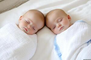 Two babies sleeping in a white blanket photo