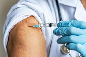 A doctor is holding an injection to a patient's arm photo
