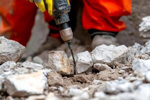 A person in orange overalls is using a drill to dig into the ground photo