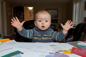 A baby sitting at a table with his hands up photo