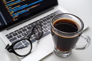 A cup of coffee and a laptop with a code on the screen photo