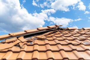A roof with a broken tile and a broken window photo