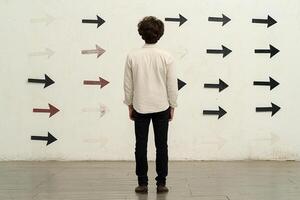 A man standing in front of a wall with arrows pointing in different directions photo