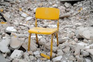A yellow chair sits in the rubble of a destroyed building photo