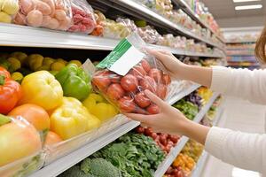 A woman is picking out vegetables in a grocery store photo