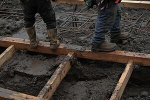 Two men standing on wooden beams while working on a construction site photo