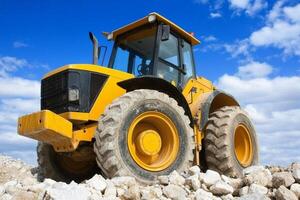 A large yellow bulldozer sitting on top of a pile of rocks photo