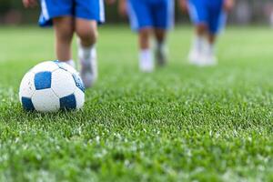 A group of children playing soccer on a grassy field photo
