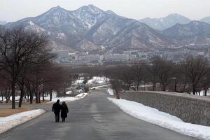A couple walking down a road with mountains in the background photo