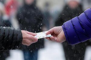 A person handing a piece of paper to another person photo
