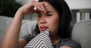 Handheld selective focus shot, An unhappy woman sits on a sofa hugging a pillow, lost in sad thoughts, feeling tense, anxious and hopeless. video