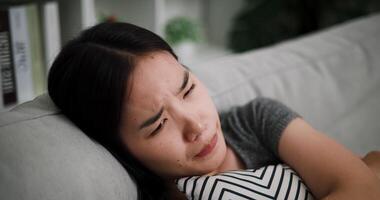 Handheld selective focus shot, A young woman is lying on a sofa, hugging a pillow, and thinking about something with stress and anxiety. video