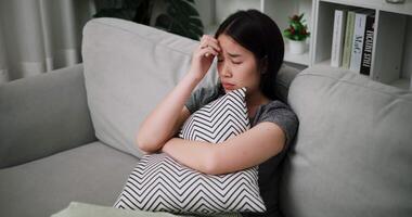 Handheld high angle view shot, An unhappy woman sits on a sofa hugging a pillow, lost in sad thoughts, feeling tense, anxious and hopeless. video