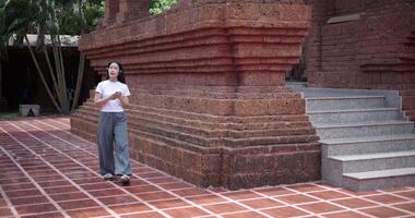 Solo female tourist enjoy takes photos with mobile phone while strolling around, admiring the peaceful atmosphere and cultural beauty of the place. video