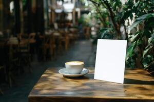 A white coffee cup sits on a wooden table next to a white sign photo