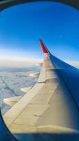 Flying on an airplane. The wing of an airplane flying over clouds with a sunset sky. View from the airplane window. photo
