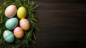 Colorful Easter eggs nestled in grass on dark wood background photo