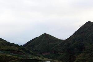 Lush Green Mountain Landscape with Scenic Hilltop and Cloudy Sky in Nature photo
