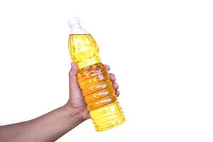 Hand holds bottle of cooking oil, isolated on white background. Extracted from seeds or from other parts of plants, such as sunflower seeds, soy beans or palm fruits. photo